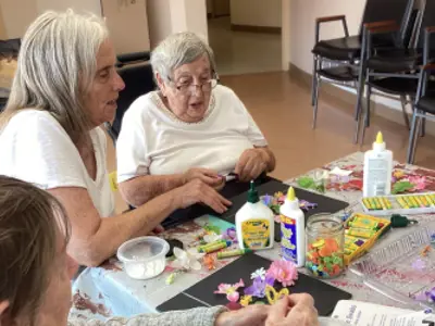 Seniors sitting at a table making art.