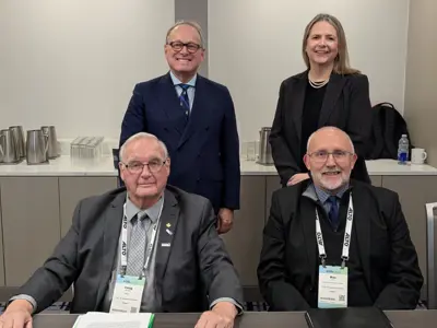 Photo of two women and two men dressed in formal business clothes facing the camera.