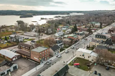 Aerial view of a small town with a central road and lake in the distance