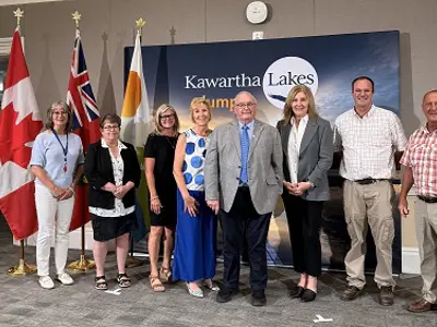 Group photo in front of brand banner for Omemee Arena project grant announcement