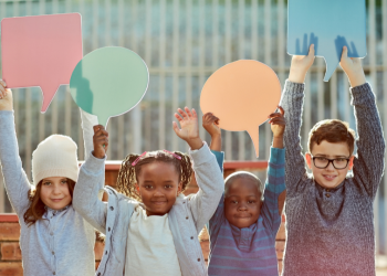 Four children hold up speach bubble cut-outs.