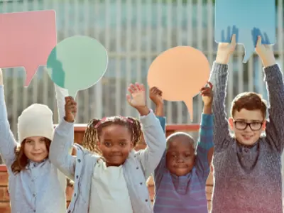 Four children hold up speach bubble cut-outs.