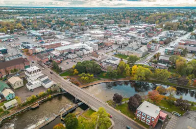Aerial view of town with a river in the foreground, trees dotting the town and a cloudy sky