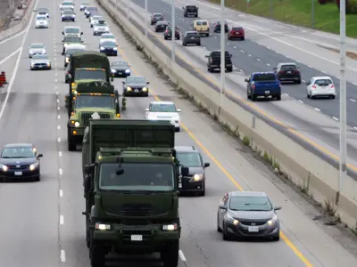 traffic on a busy highway with army vehicles in the middle lane