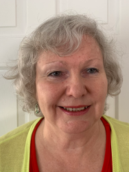 Adult woman with white hair, wearing a yellow cardigan.