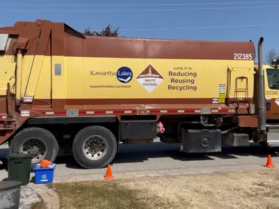 A waste collection truck stopped on the side of a road