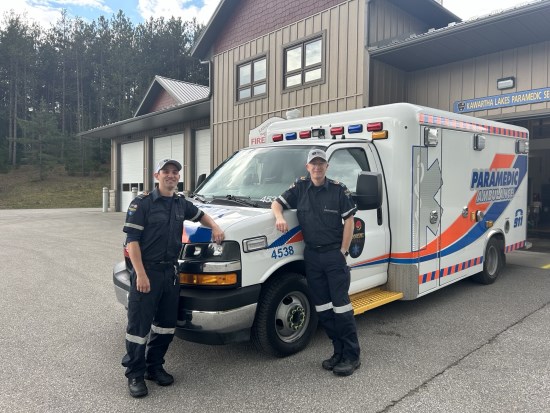 Paramedics wearing staff appreciation hats outside and leaning against an ambulance