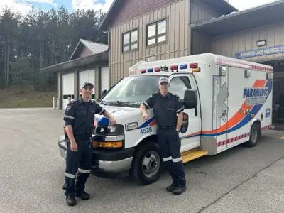Paramedics wearing staff appreciation hats outside and leaning against an ambulance
