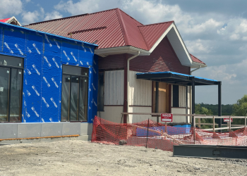An old building with a large new addition under construction.