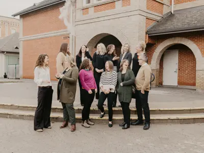 A group of women standing candidly in front of a brink building