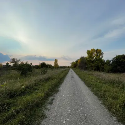 Gravel path through grassy area against a cloudy sunset