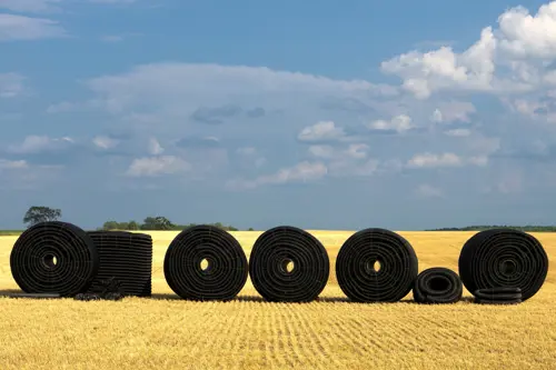 Tile drain pipes in field of harvested wheat with storm clouds in the background
