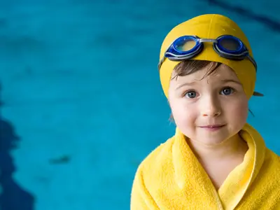 Young camper wrapped in a yellow towel after their swim