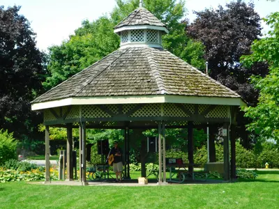 Gazebo in green park with person playing music inside