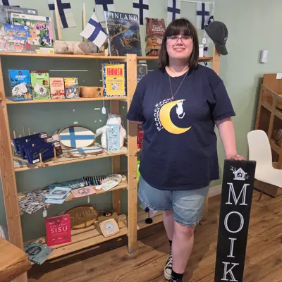 Young woman standing in front of a display shelf of retail items.