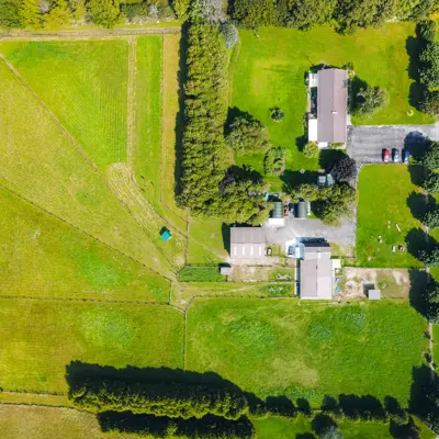 Aerial view of green land with barn, buildings and trees