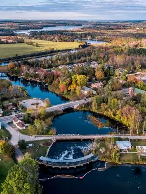 Aerial view of river with multiple bridges overtop and town buildings and houses surrounding the town