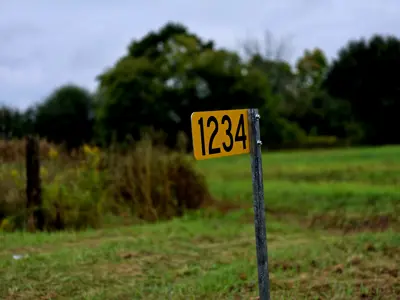 Yellow sign featuring a 911 sign against a rural backdrop