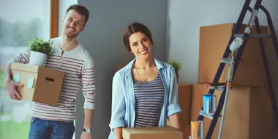 Two people moving boxes inside