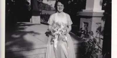 Black and white photo of woman in wedding dress holding a bouquet.