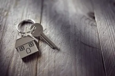 Key with house key chain against a grey wooden background