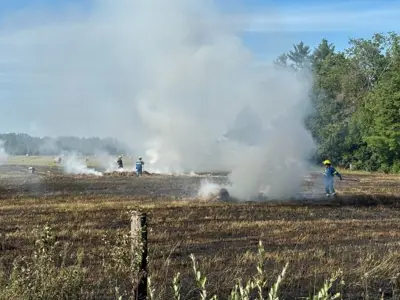 Firefighters putting out a fire in a farmer's field