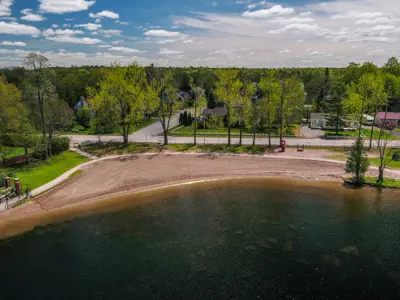 Aerial view of sandy beach with trees and neighbourhood nearby