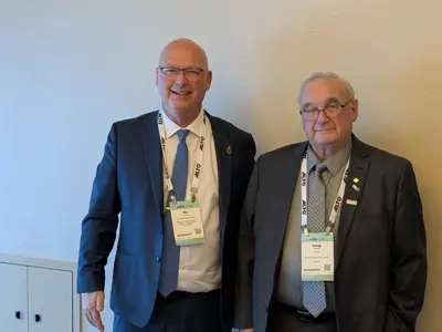 Photo of two smiling men in suits, wearing conference lanyards.