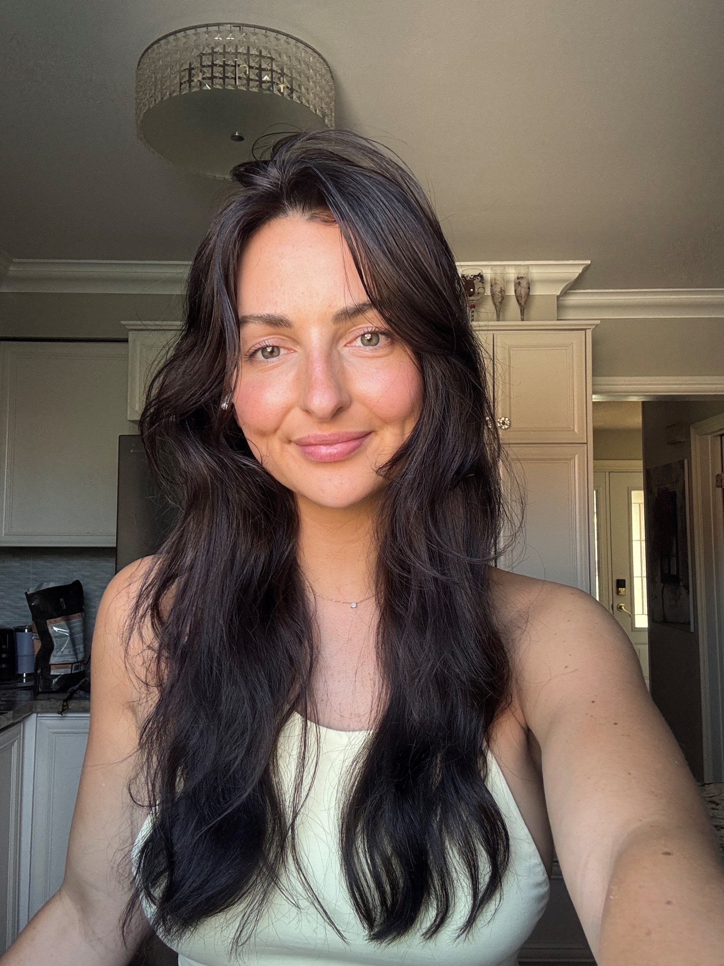 Female with long dark hair wearing a yellow sleeveless top.