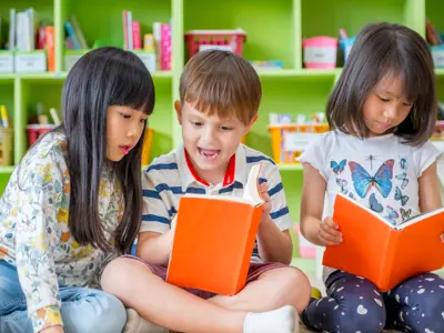 Three children sitting on the ground reading books