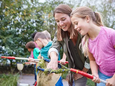 camper and leader dicovering what lies beneath the water holding net during eco adventure camp