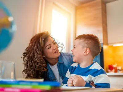 Camper and his caregiver laughing and crafting at summer day camp