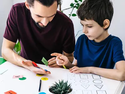 Caregiver working with one of our Inclusion Day Campers on a project at camp