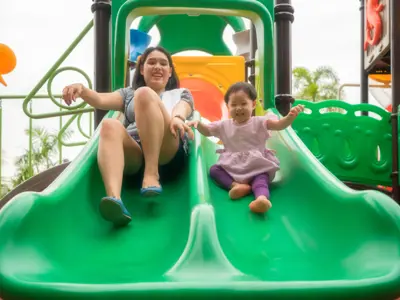 Woman and child going down a green double slide