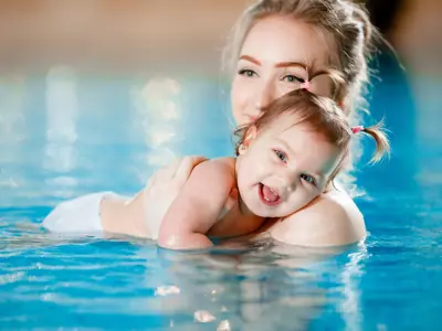 Women holding young child in a pool