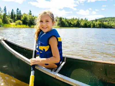 Young camper wearing a lifejacket and learning how to canoe