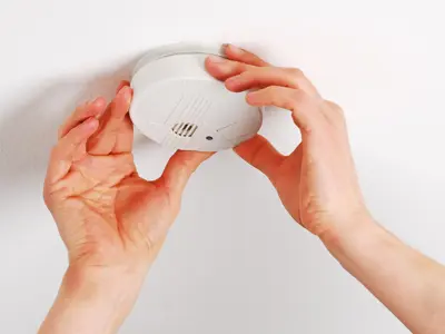 Pair of hands installing a smoke alarm