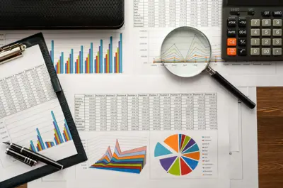 Assorted financial data sheets with calculator, magnifying glass and pen