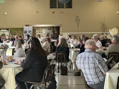 A room filled with people seated at tables